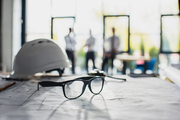 various architecture supplies on workplace with architects behind, focus on foreground