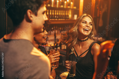 Young woman having drink at nightclub with friends