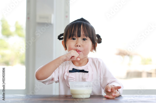 Little child girl eating and tasting ice cream, Child girl licking her fingers.