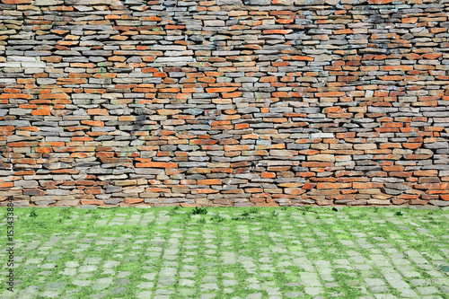 Matural urban background. Stone wall and cobbled floor with some grass. photo