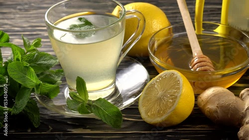 Ginger tea with lemon, mint and honey on wooden background.