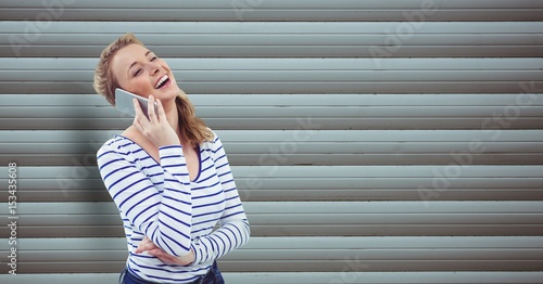 Happy woman using mobile phone against wall