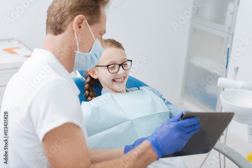Witty cool dentist educating little patient