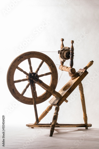 Old wooden spinning wheel on white background