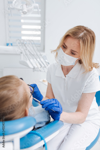 Careful nice competent dentist working in mask