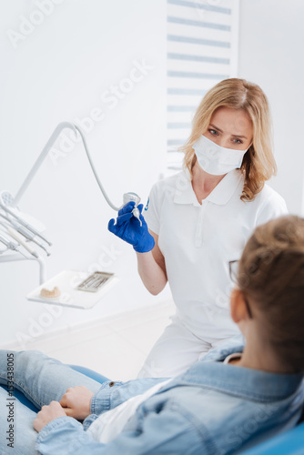 Gentle experienced dentist starting treatment process