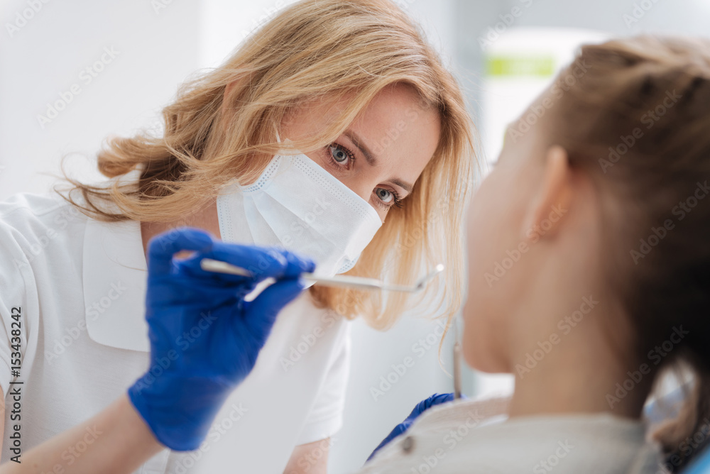 Mindful qualified doctor carefully examining girls teeth Mindful qualified doctor carefully examining girls teeth