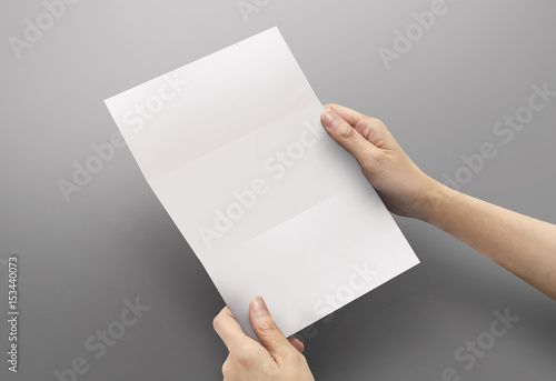 Hands holding paper blank a4 size for letter paper on grey background