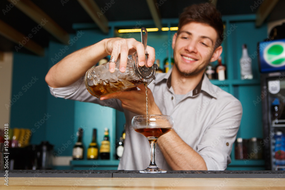 Young Barman mixing cosmopolitan cocktail