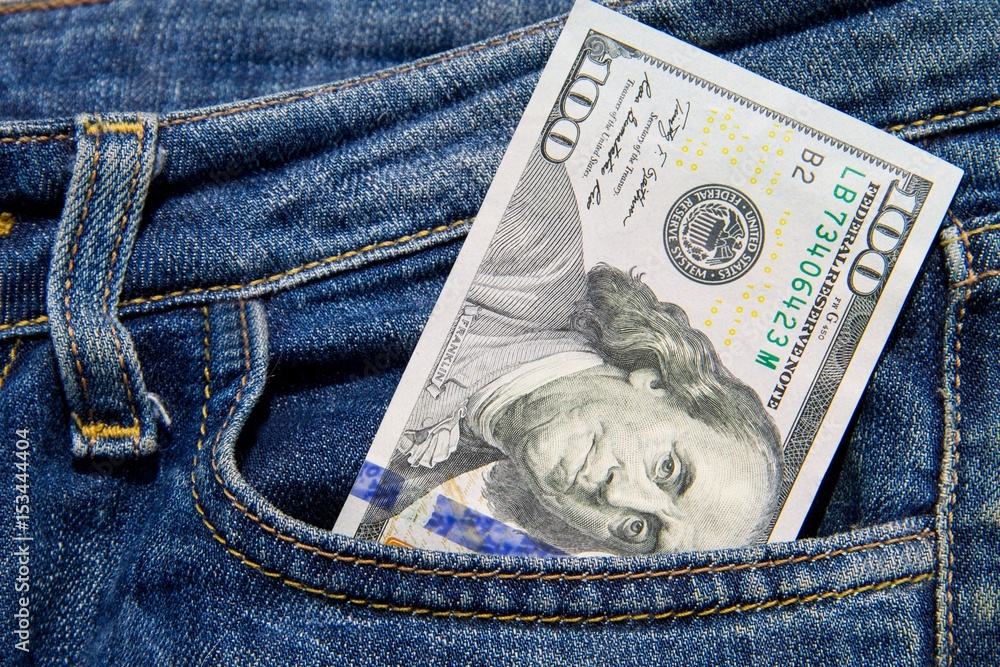 One hundred American dollars bill in the pocket of blue jeans One hundred American dollars bill in the pocket of blue jeans