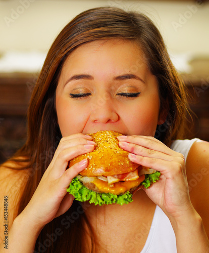 Close up of a beauty woman in cafe eating a delicious hamburger