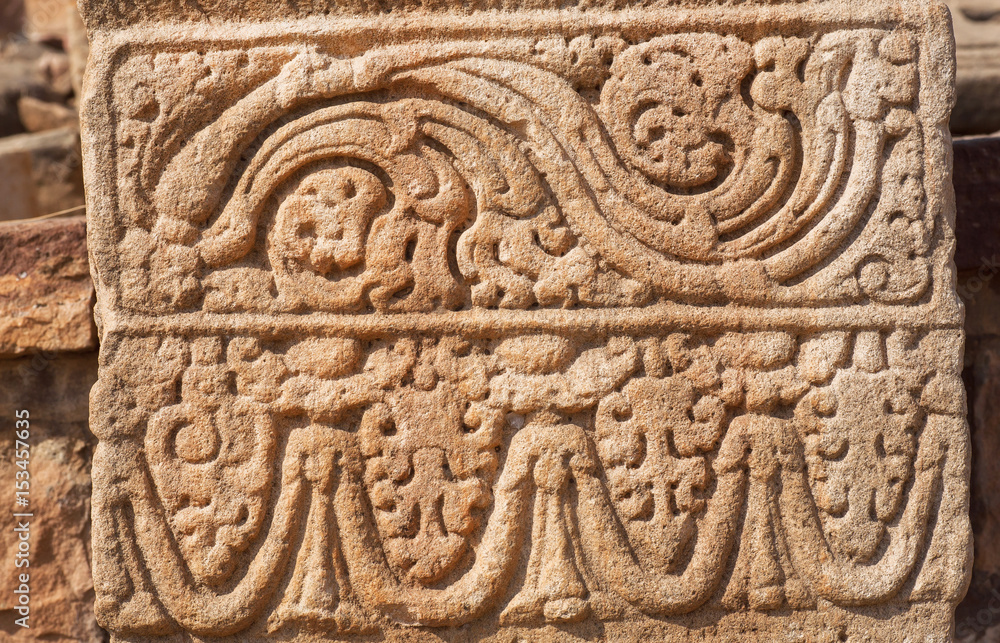 Patterned design of stone relief on wall of 7th century temple in Pattadakal of Karnataka, India. UNESCO World Heritage site with stone carved temples