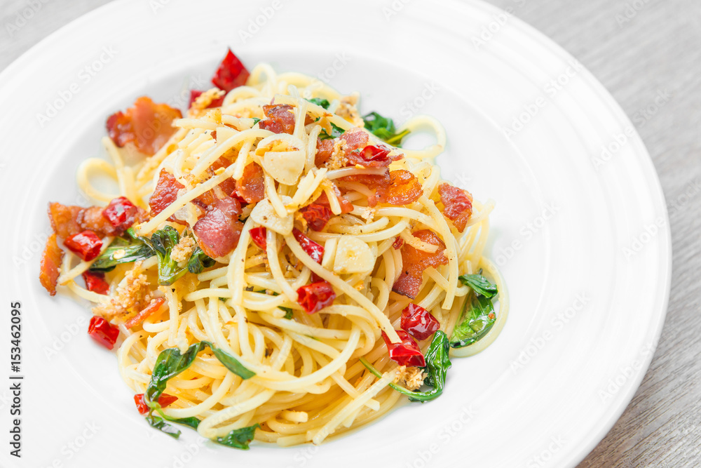 Spaghetti with fried crispy bacon and chili fried basil leave hot and spicy food delicious international cuisine in Thailand style