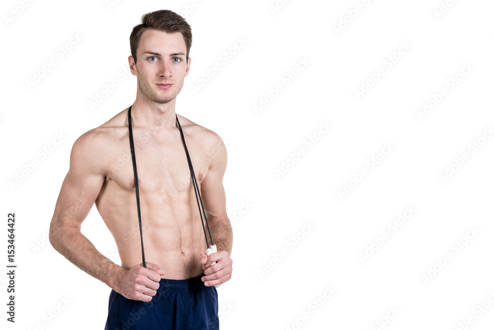 Fototapeta premium Healthy lifestyle and fitness. Handsome guy sports a physique, with a naked body, with a skipping rope in his hands, isolated on a white background. Horizontal frame