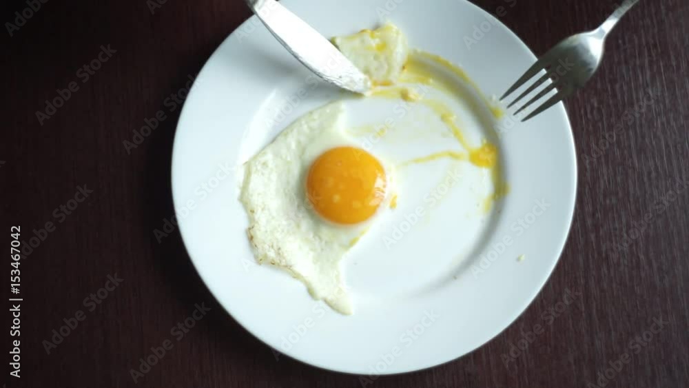 Finish eating fried eggs. Male hand cutting fried egg with knife and fork. Close up of cutting fried eggs. Finishing morning breakfast. Traditional breakfast. Healthy breakfast. Crossed cutlery Finish eating fried eggs. Male hand cutting fried egg with knife and fork. Close up of cutting fried eggs. Finishing morning breakfast. Traditional breakfast. Healthy breakfast. Crossed cutlery