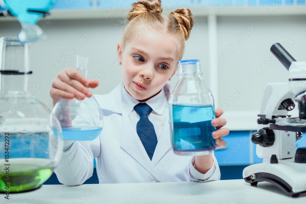 schoolgirl in white coat making experiment with reagents in chemical lab, science student concept schoolgirl in white coat making experiment with reagents in chemical lab, science student concept