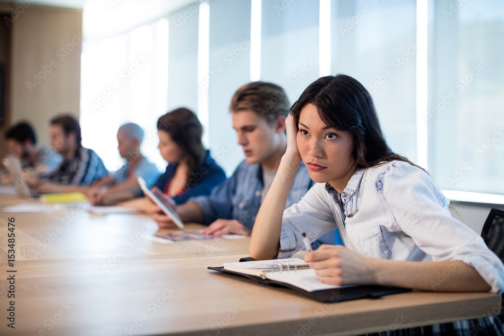 Woman sitting in meeting room with her colleagues Woman sitting in meeting room with her colleagues