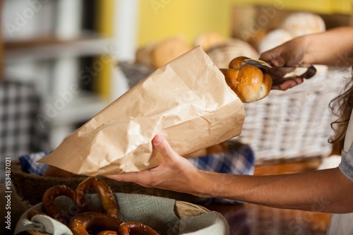 Staff packing bread in paper bag at bakery shop