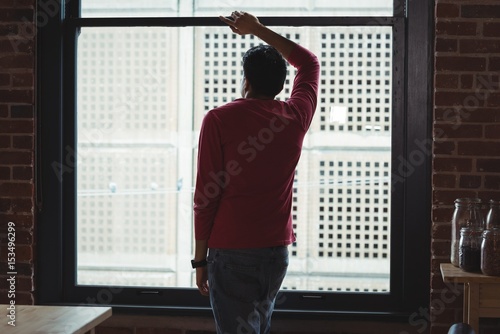 Thoughtful man looking through window at home