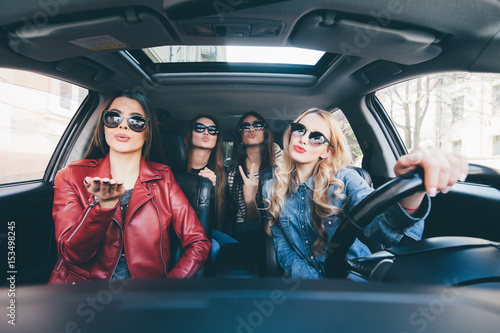 Group of friends having fun whet drive the car. Singing and laughing on the road