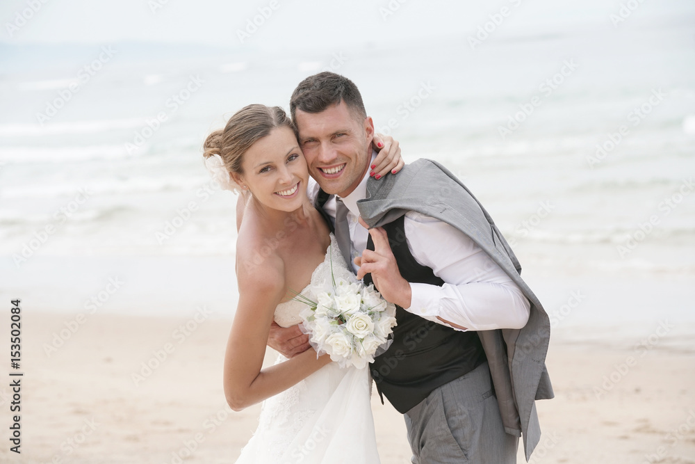 Portrait of happy bride and groom embracing each other at the beach Portrait of happy bride and groom embracing each other at the beach