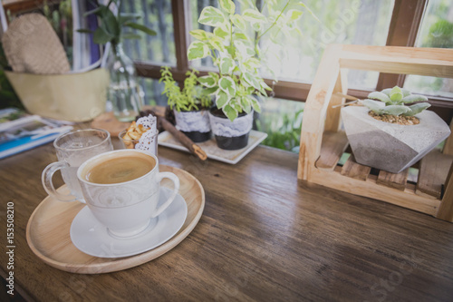 Cup of hot coffee in circle wooden tray on wooden counter in coffeeshop