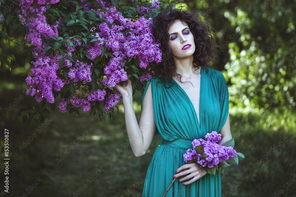 Woman luxuriates in lilac bushes, she closes her eyes and inhales the fragrance of flowers. Woman luxuriates in lilac bushes, she closes her eyes and inhales the fragrance of flowers.