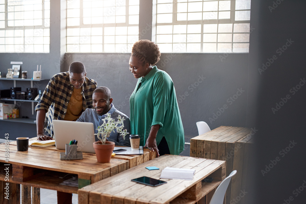 African businesspeople using a laptop together in a modern office African businesspeople using a laptop together in a modern office