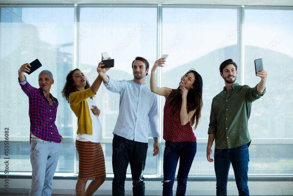 Fototapeta premium Creative business team taking selfie with mobile phone