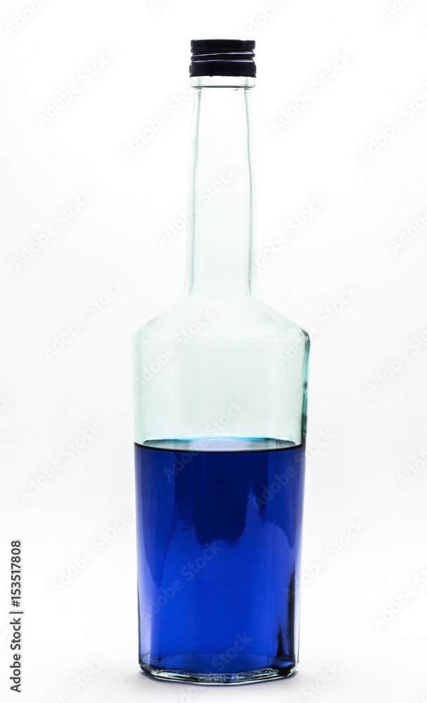 Blue alcohol bottle isolated. A half-filled bottle of blue alcohol. Blue alcohol bottle isolated. A half-filled bottle of blue alcohol.