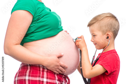 Little boy listens to his mother's pregnant belly. isolated on white background