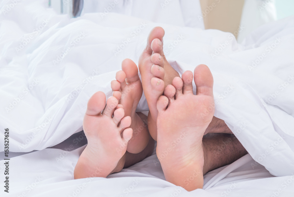 Feet of couple side by side in bed Feet of couple side by side in bed