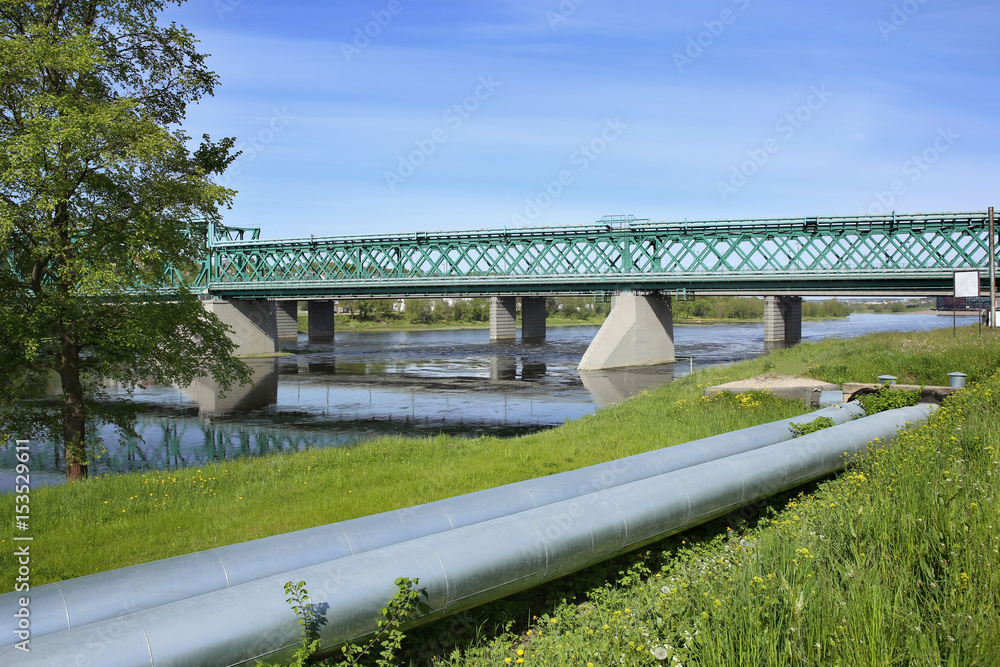 Railway bridge and industrial pipes. Kaunas, Lithuania – May 17, 2017: Industrial landscape with Green Railway Bridge and pipes.