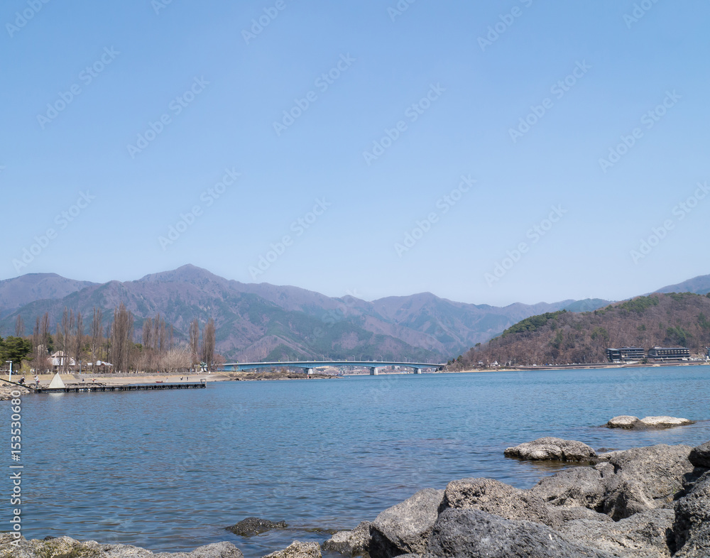 Fototapeta premium Landscape of the bridge over lake Kawaguchi, mountain and blue sky - Kawaguchiko, Japan