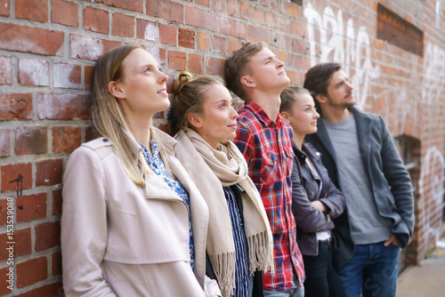 junge leute stehen zusammen und schauen nachdenklich nach oben photo