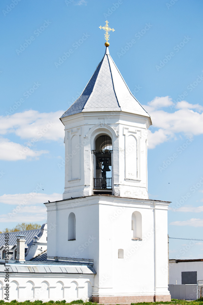 white bell tower of the old monastery on the background of blue sky