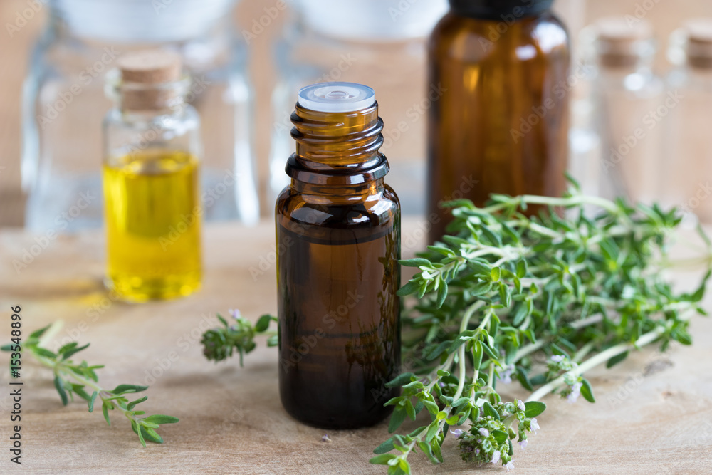 A bottle of thyme essential oil with fresh thyme twigs A bottle of thyme essential oil with fresh thyme twigs