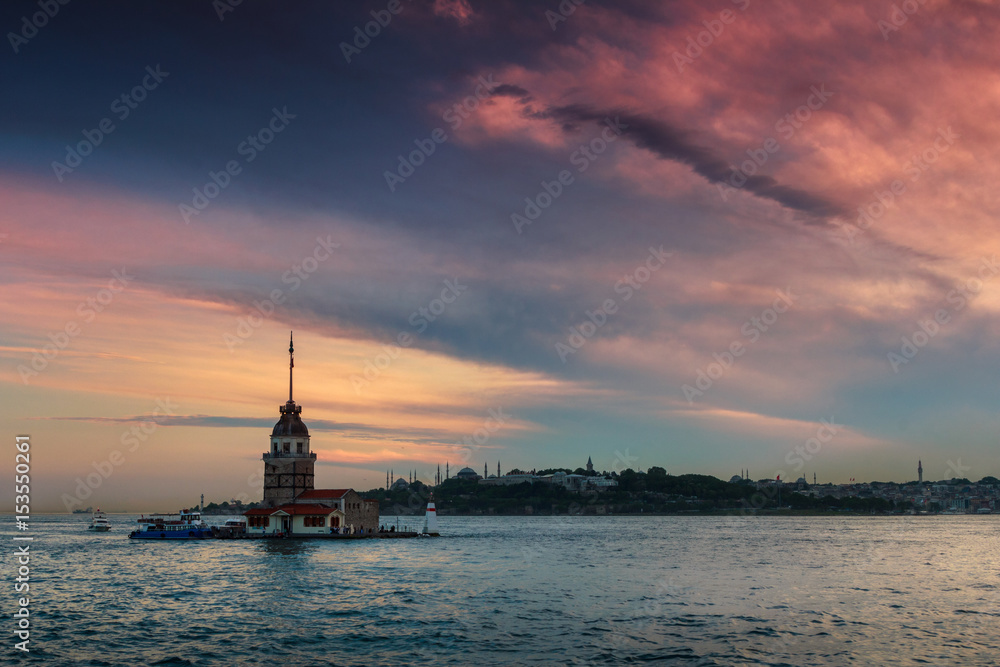 Beautiful landscape of Maiden's tower (Tower of Leandros) at sunset. Dramatic cloudy sky. In the distance are such landmarks as Hagia Sophia, Blue Mosque and Topkapi Palace. Istanbul. Turkey.