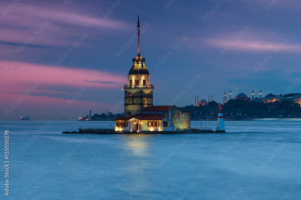 Beautiful landscape of Maiden's tower (Tower of Leandros) from shore. Night View on Istanbul. In the distance are such landmarks as Hagia Sophia, Blue Mosque and Topkapi Palace. Turkey.