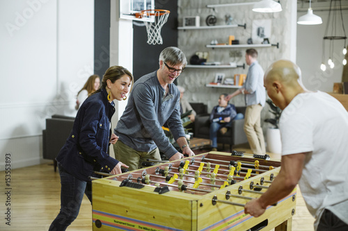 Business people playing foosball in office photo