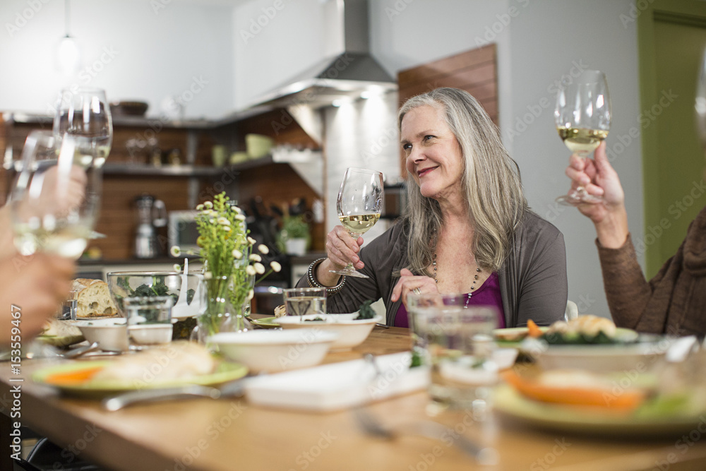 Friends with wineglasses sitting at table during social gathering Friends with wineglasses sitting at table during social gathering