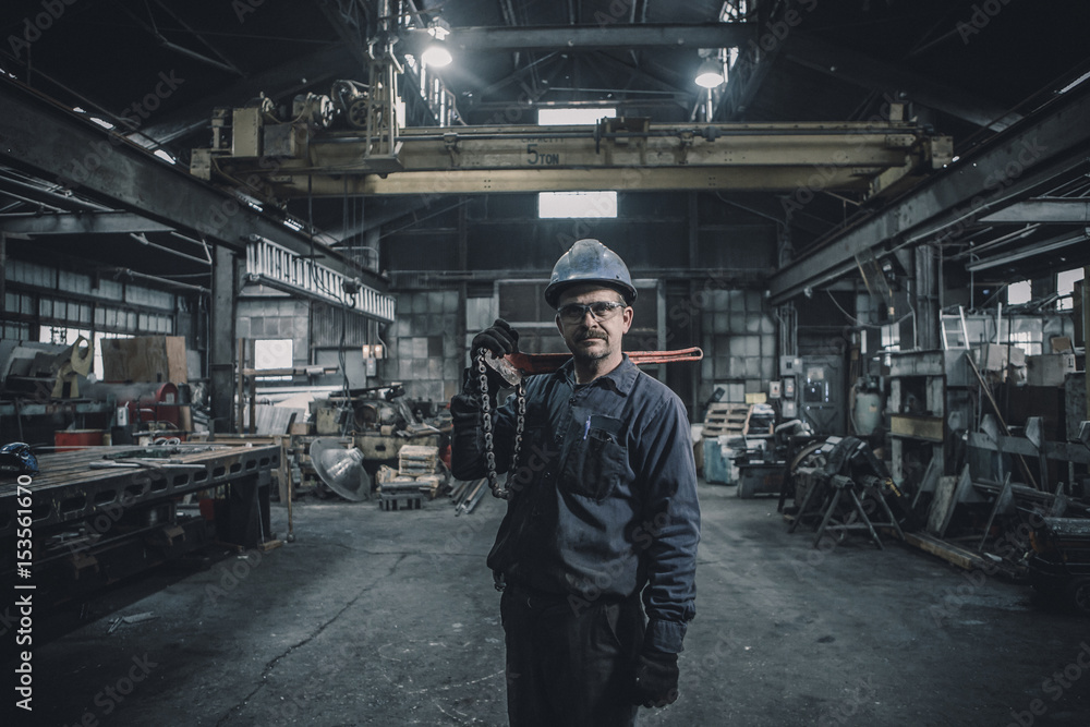 Portrait of worker carrying work tool while standing in factory Portrait of worker carrying work tool while standing in factory