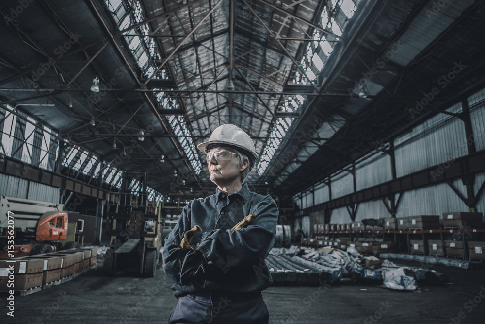 Female worker with arms crossed looking away while standing in factory Female worker with arms crossed looking away while standing in factory