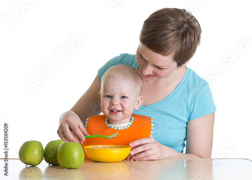 Mother spoon-feeding her ba...