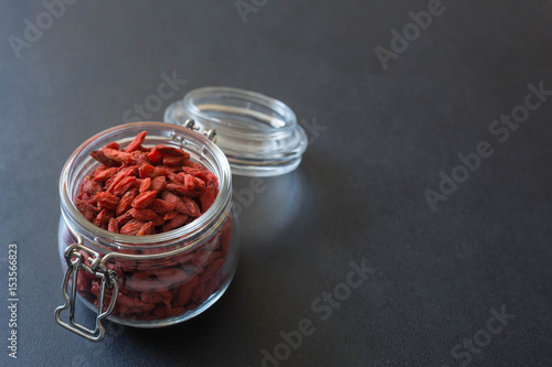 dried Goji berried in a jar on the dark stone background.