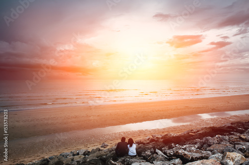 future together concept. landscape of couple lover people sitting together on the beach looking forward to the sea with sunset light.