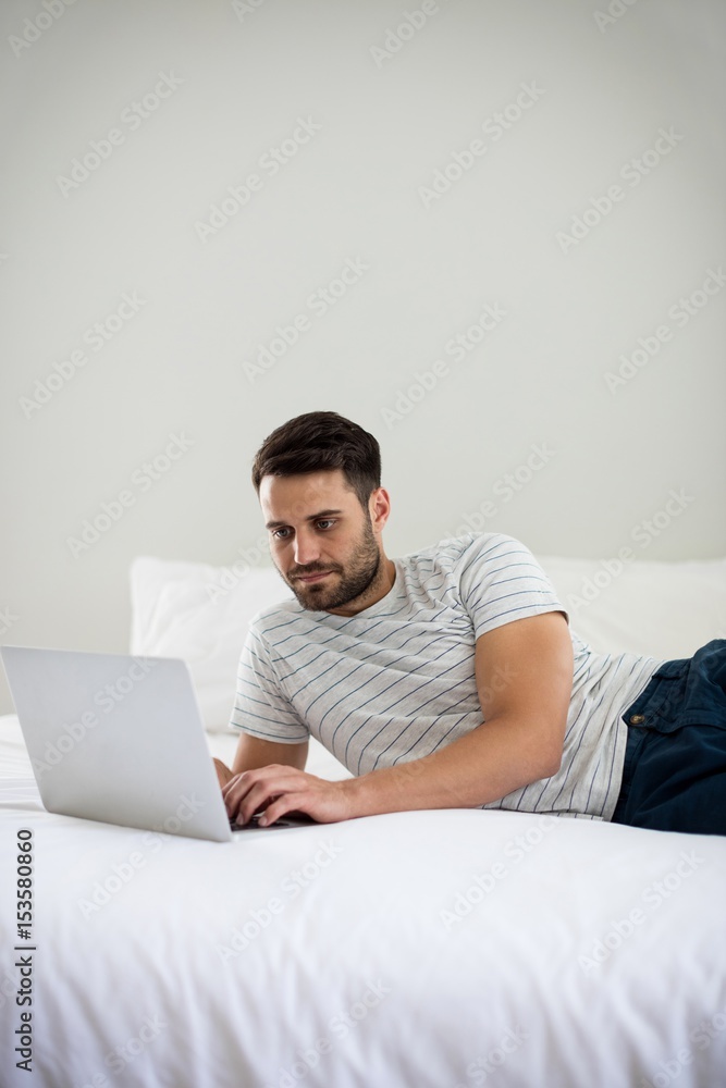 Man using laptop on bed Man using laptop on bed