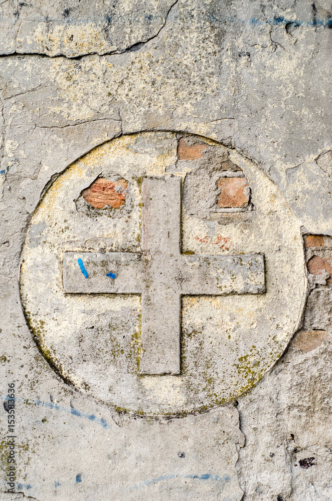 Cross symbol on a old, ruined wall