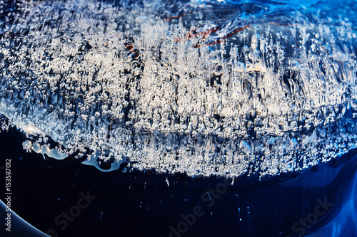 Frozen gas bubbles settle on the air cavity in the ice. A beautiful natural phenomenon. Greenhouse effect. Colorful blue cool colors. Abstract background. Frozen, unique ice bubbles.. photo