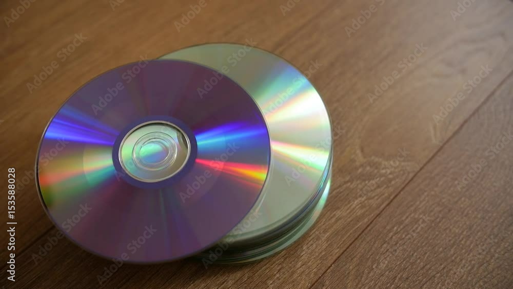 Closeup of a stack compact discs on wooden floor background. Cd falling from the top, slow-motion. Closeup of a stack compact discs on wooden floor background. Cd falling from the top, slow-motion.